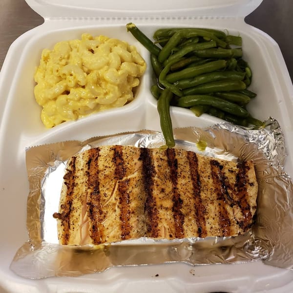 Grilled salmon with mac and cheese and green beans in a white takeout container.