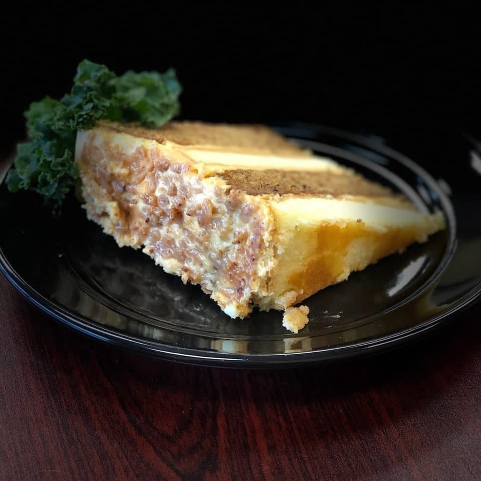 A slice of L&G Southern Soul Food's caramel cake with nuts and a kale garnish.