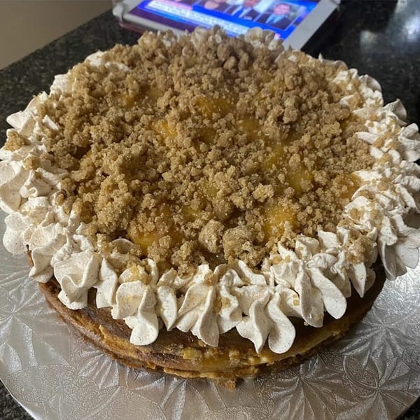A whole southern soul food dessert, possibly a cheesecake, topped with crumble and whipped cream.